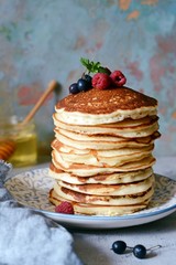 A stack of lush punkcakes for breakfast on a gray background. High pile of delicious pancakes with berries.American Cuisine, Copy space