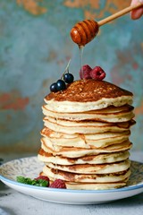 A stack of lush punkcakes for breakfast on a gray background. High pile of delicious pancakes with berries.American Cuisine, Copy space