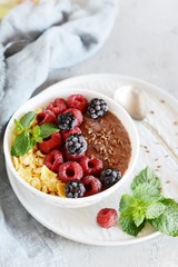 Sunday Breakfast. Oatmeal porridge with banana and flax seed, raspberries, blackberries, corn flakes, honey and mint, selective focus. Useful food, diet. Plate or cup with vegan porridge, smoothies 
