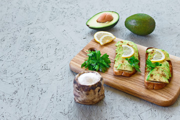 The concept of proper nutrition. Vegetarian menu. Toasts with avocado, lemon, chilli or paprika on a gray background