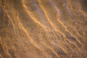 background texture of transparent waves of water on a sandy beach at a resort