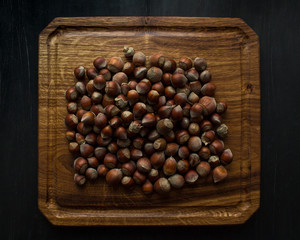 hazelnut nuts on wooden cutting board on black background