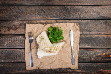 Tortilla wrap with chicken breast and vegetables. Served with cutlery on a wooden background.