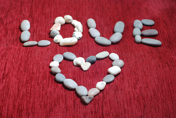 Heart made  of sea stones on a red velvet