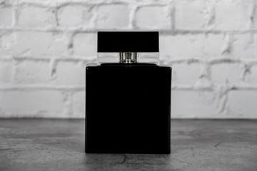 Mock up of a black bottle of men's perfume on a brick gray wall background. Place for text.
