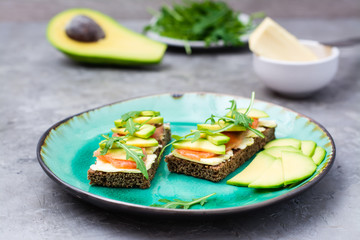 Tasty bruschetta with salmon, butter, avocado and arugula on a plate