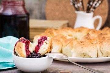 Still life with pieces of monkey bread and berries jam on a wooden table. Rustic style