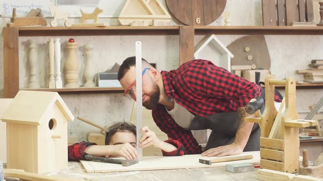 Father and little son giving high five while visiting woodworking masterclass at workshop