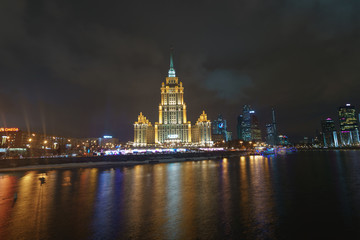 Hotel Ukraine (Radisson Royal Hotel) in bright lights and Moskva river in night winter reflections of the night Moscow.. MIBC (Moscow International Business Center) as background.
