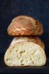 Fresh homemade bread on a dark background, on whole wheat flour. French bread round shape. Bread baking. Unleavened bread