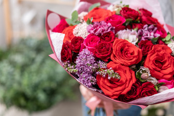 beautiful fresh cut bouquet of mixed flowers in woman hand. the work of the florist at a flower shop. Red color