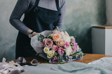 Девушка флорист собирает красивый букет girl florist makes a beautiful bouquet - obrazy, fototapety, plakaty