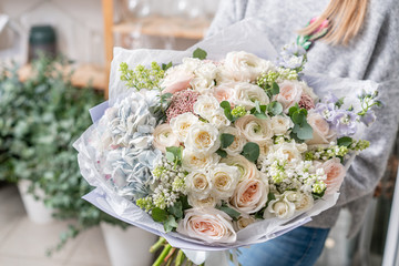 beautiful fresh cut bouquet of mixed flowers in woman hand. the work of the florist at a flower...