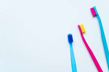 Colorful tooth brushes with bright color bristles on a light pastel blue background. Dental tools with empty space for text for  your mockup.