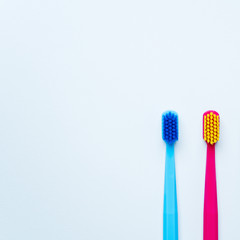 Colorful tooth brushes with bright color bristles on a light pastel blue background. Dental tools with empty space for text for  your mockup.