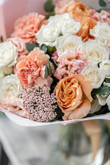 beautiful fresh cut bouquet of mixed flowers in vase on wooden table. The work of the florist at a flower shop. Delicate Pastel tones color