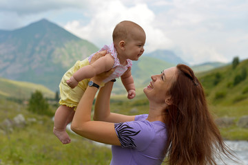 Young mother with a small child in a backpack-carrying travels in the mountains in the summer