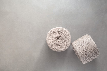 Two skeins of wool yarn on a light gray paper background