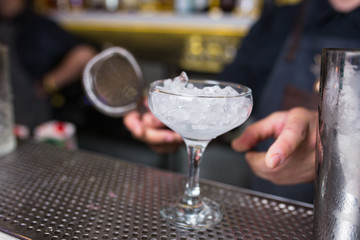 Bartender ice cube freezing the glass drink before preparing cocktail -beverage on a bar counter  .Close up  view . Trendy stylish edit . Copy paste space for design concept service waiter concept