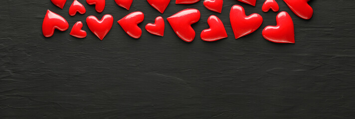 Collection of shiny red hearts on dark rough background