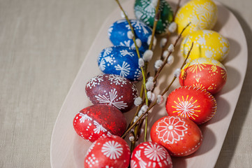Easter background. Eggs in wooden plate, painted with wax and food colors. Close up, soft focus, top view. Easter holiday concept.