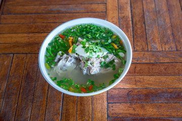 Hot and Spicy Soup with Pork Ribs. Spicy Pork with Pork bone Soup on the Wood Table. Leng soup in Thai word. Hot and spicy pork spare rib soup with tamarind and Thai herbs in bowl, Tom yum.