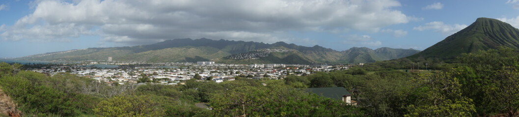 Fototapeta na wymiar Panorama view of land in Honolulu, Hawaii. Green land with blue sky and big clouds.
