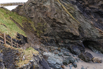 a ravine between the mountains that go to the sea; the wooden staircase with wooden fence leads down from the rocks to the water that has retreated during low tide