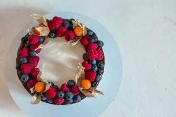 Obraz na płótnie Canvas chocolate sponge cake covered with white cream and decorated with fresh berries