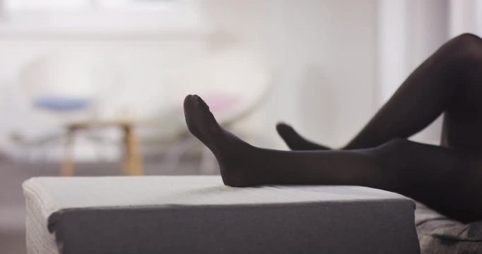 young woman puts her legs up while wearing tights in a lovely livingroom