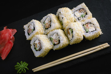 Sushi rolls on a dark plate.