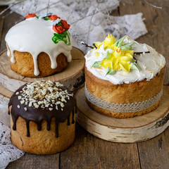 Easter cake kulich. Traditional Easter sweet bread decorated meringue, chocolate and yellow daffodils on wooden background with lace fabric. Copy space, selective focus, close up.