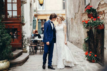 stylish bride and groom walking and embracing in city street.  luxury wedding couple hugging....
