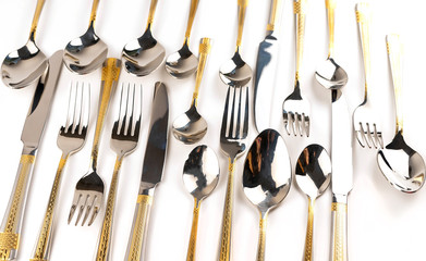 Different cutlery - forks, spoons and knives on a white background