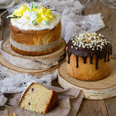 Easter cake kulich. Traditional Easter sweet bread decorated meringue, chocolate and yellow daffodils on wooden background with lace fabric. Copy space, selective focus, close up.