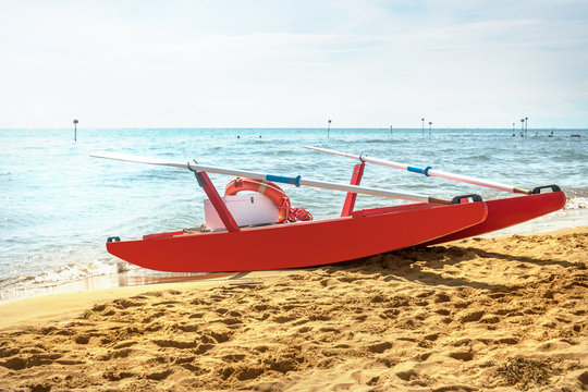 red wooden rescue boat with oars and a lifeline on the seafront on a sandy beach