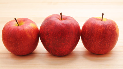 Three red apples on the table.