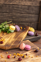 Varicolored tasty macaroon cookies lie on a wooden background with a cup of coffee. Continental breakfast.