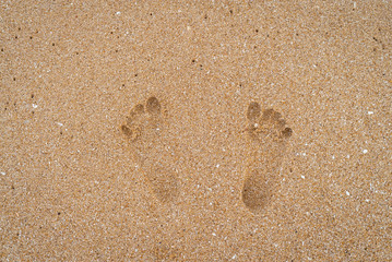 Fototapeta na wymiar Closeup of footprints in the sand on the beach in sunny time. The symbol of relaxation and slowlife.