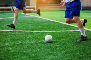 Obraz premium Asian student play plastic soccer ball on green artificial turf