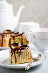 A heart-shaped cupcake decorated wiht chocolate. A cup of cocoa.