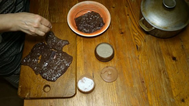 Homemade cooking. Cooking liver steaks or meat for frying. Chef sprinkle spices and salt raw beef liver or meat steak on wooden cutting board.