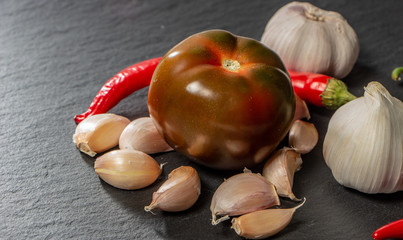 A still-life of heads of garlic on a slate background