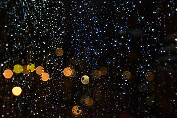 Drops of rain on window with bokeh of lights on background