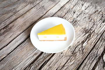 Slice of lemon cheesecake  in plate on wooden table