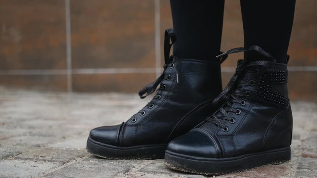 Female legs in boots on the sidewalk