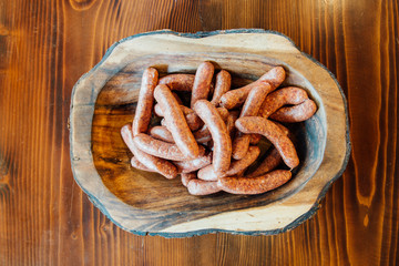 Raw sausages in plate on wooden table