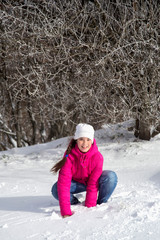 Portrait of a girl in the winter outdoors playing with snow.