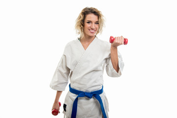 Portrait of female wearing martial arts costume training with dumbbells