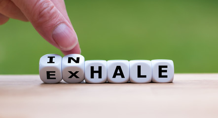 Inhale,Exhale concept. Hand turns dice and changes the word "INHALE" to "EXHALE".